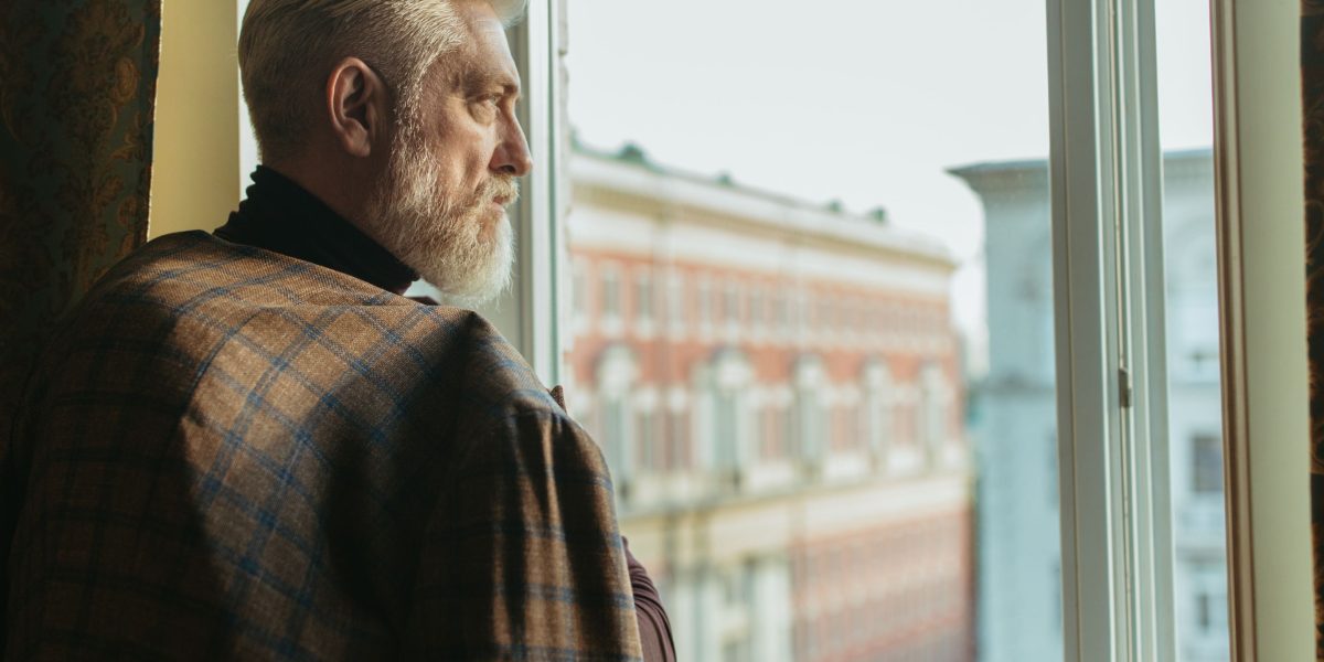 A person thoughtfully looking out, contemplating new investment opportunities in luxury real estate.