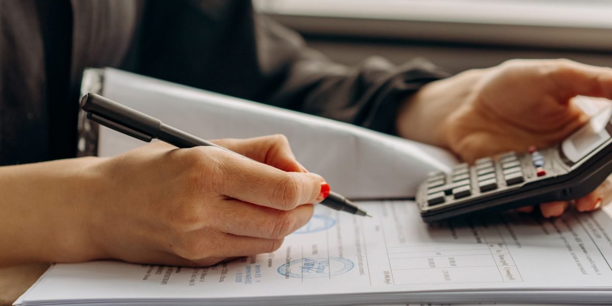 A person meticulously reviewing financial documents, symbolizing the detailed planning required for property investment.