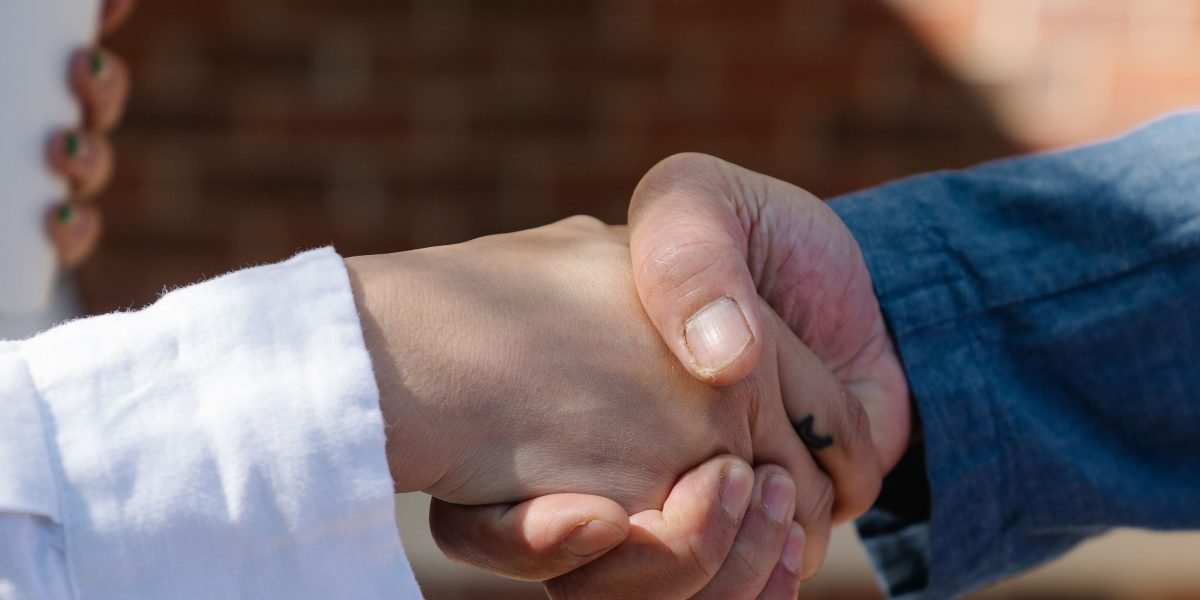 Two professionals are seen shaking hands after successfully signing legal documents for a property deal.